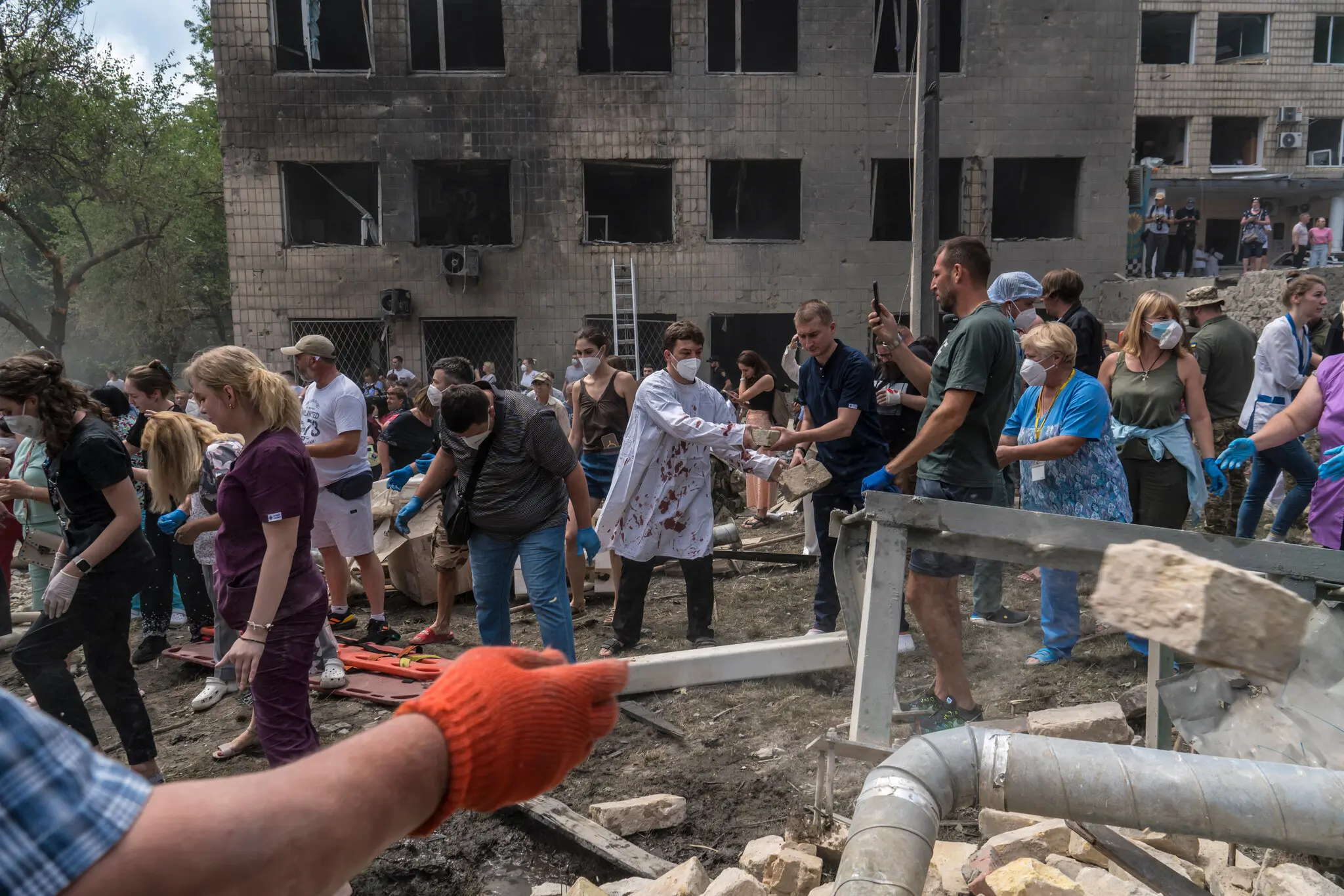 Хірург у закривавленому халаті допомагає рятувальникам і волонтерам розчищати завали.